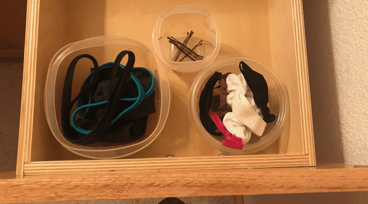 Hair accessories in plastic containers in a drawer